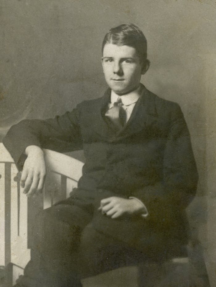 Services Classic antique portrait of a young man in a formal suit, sitting elegantly.